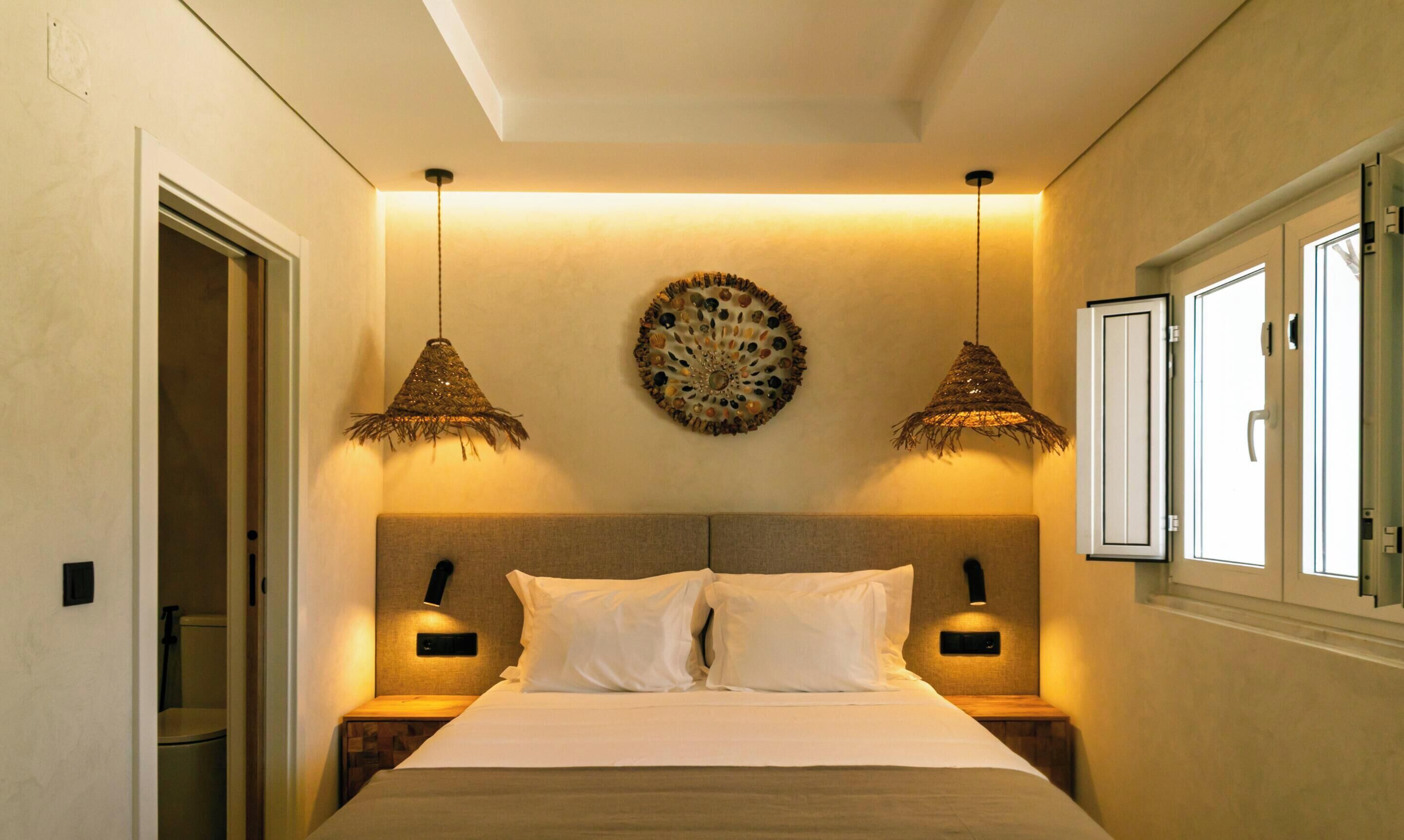 A bedroom with a bed, two bedside lamps, a wall-mounted decorative item, and a window with a door.