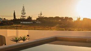 A swimming pool with a view of a grassy field and trees in the background. - MyStay - Aunt Olinda (Porto Covo)