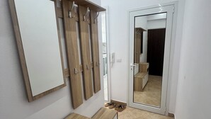 Un pasillo con un armario de madera, un espejo y una puerta que da a otra habitación.