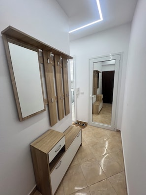 A hallway with a wooden wardrobe, a mirror, and a door leading to another room. - AA Holiday Apartment Longmore Vlore (Lungomare)