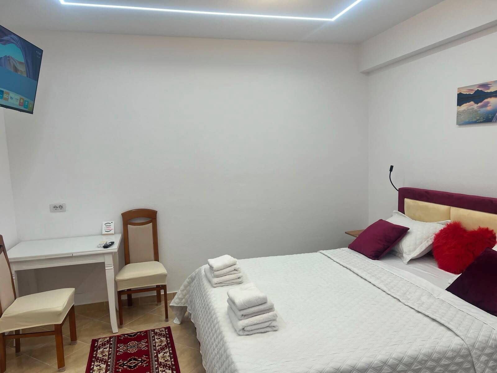 A hotel room with a bed, a desk, a chair, and a small rug.