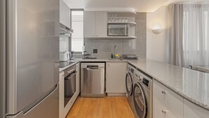 A modern kitchen with stainless steel appliances, a dishwasher, a washing machine, and a microwave. - Dolce Vita | Luxury 3 bed Retreat (Cape Town)