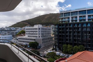 A modern hotel with a flat roof, large windows, and a view of a cityscape with buildings and a hill in the background. - Dolce Vita | Luxury 3 bed Retreat (Cape Town)
