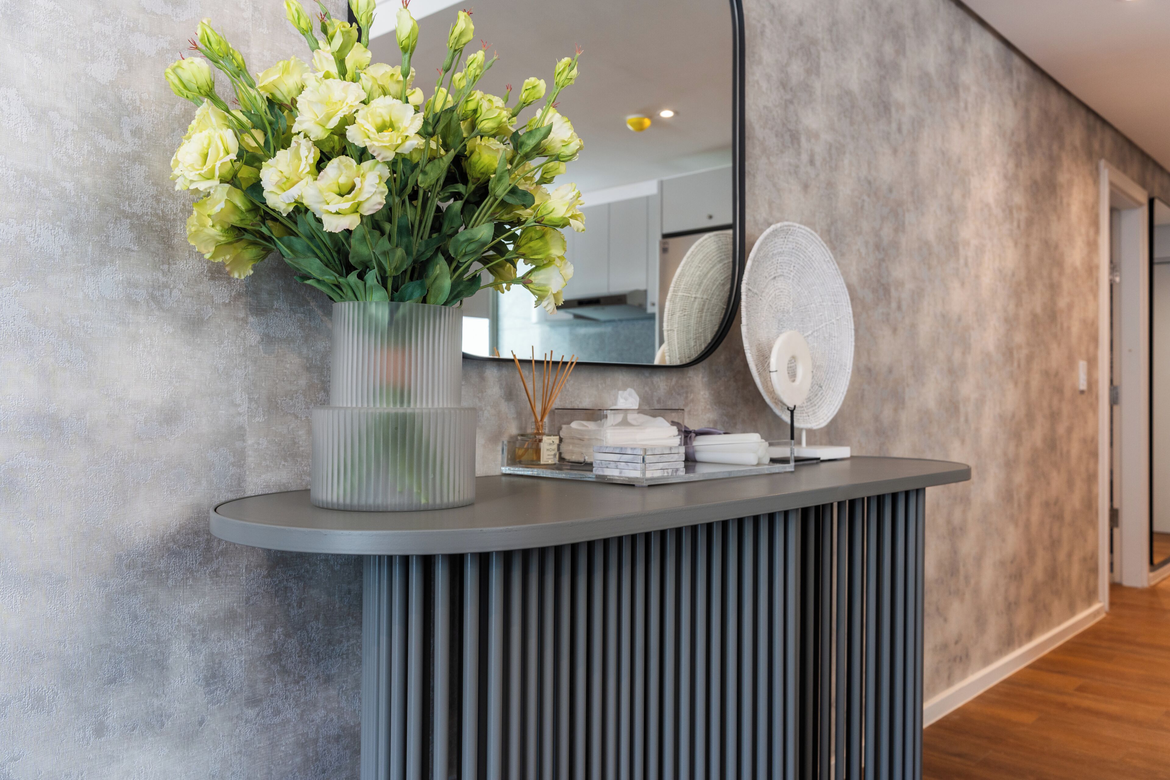 Un comptoir d’accueil agrémenté d’un vase de fleurs, d’un miroir et d’un ventilateur.