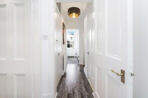 A hallway with white doors, a wooden floor, and a ceiling light fixture. - Modern - 2BR Flat near Easter Road Stadium (Edinburgh)