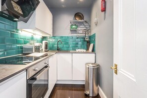 Une petite cuisine équipée d’une cuisinière à gaz, d’un grille-pain et d’un évier.