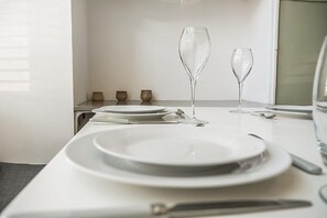 Une table à manger dressée avec des assiettes, des couverts et deux verres.