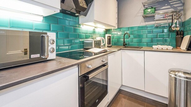 Una cocina moderna con microondas, tostadora y horno, un fregadero y un botiquín en la pared.