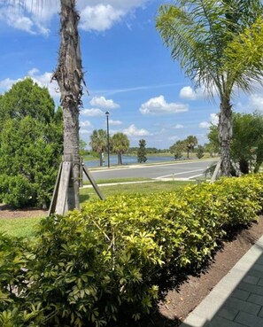 A paved pathway alongside a body of water, with trees and a clear sky. - Charming 2-bedroom Villa on water w/ Many Amenities in gated Lakewood Ranch (Bradenton)
