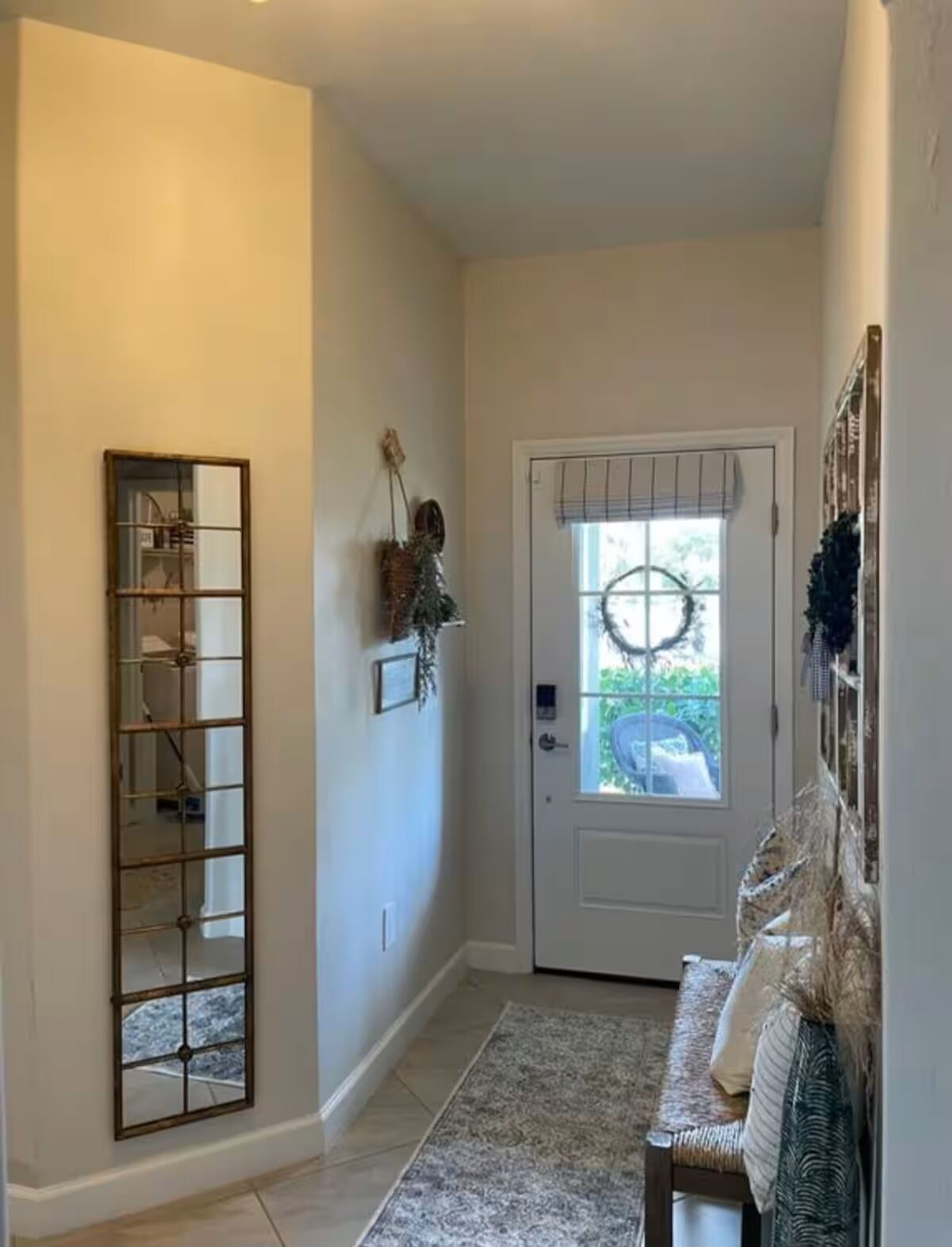 A hallway with a door, a mirror, and a bench.