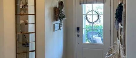 A hallway with a door, a mirror, and a bench.