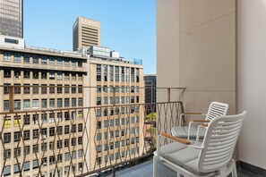 A balcony with two white chairs, a view of a building with 'LUNO' signage, and a clear sky. - Charlie and the Chairman Modern CBD Retreat (Cape Town)