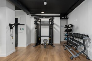 A gym with a squat rack, dumbbells, and resistance bands. - The Tokyo | Rooftop Pool | No Loadshedding (Cape Town)