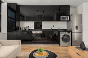 A modern kitchen with a microwave, refrigerator, oven, and washing machine. - The Tokyo | Rooftop Pool | No Loadshedding (Cape Town)