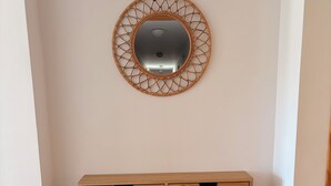 Un mueble de madera con cuatro cajones y un espejo redondo con un marco geométrico en la pared.