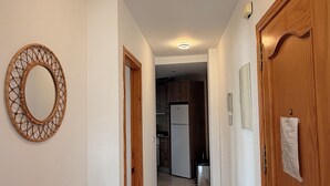 Un pasillo con un armario de madera, un espejo circular y una puerta con un papel adherido.
