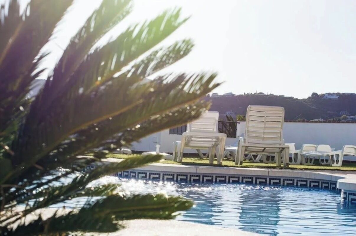 A pool area with lounge chairs and a view of a distant landscape.