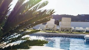 Zona de piscina con sillones de descanso y vista a un paisaje lejano.