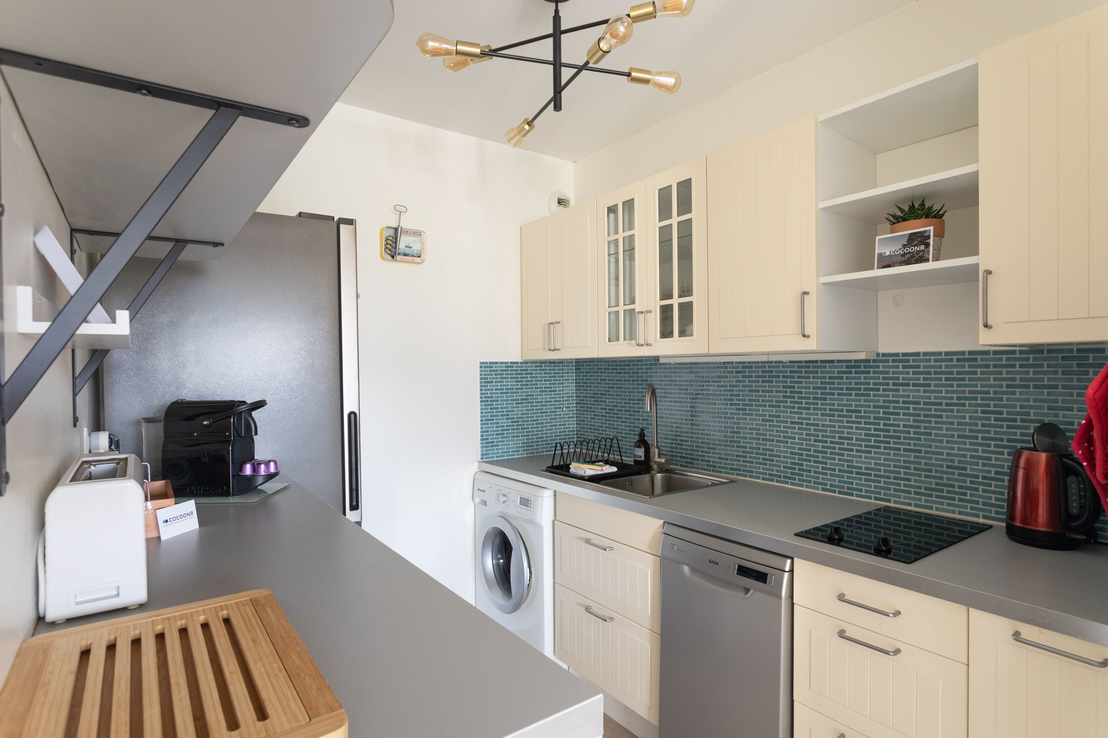 A modern kitchen with a built-in washing machine, a coffee machine, and a kettle.