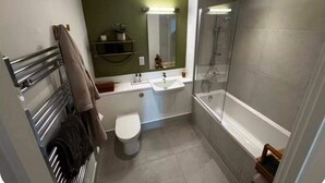 A modern bathroom with a glass-enclosed shower, a toilet, and a sink. - Cozy London Apartment With 2 Bedrooms (London)