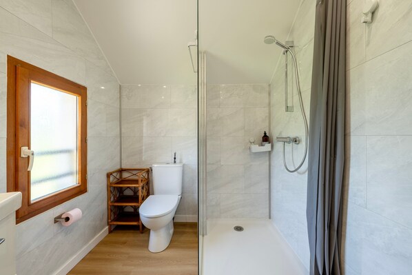 Ein Badezimmer mit Toilette, Dusche und einem Fenster.