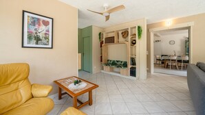 Ein Wohnzimmer mit einem gelben Sofa, einem kleinen Holztisch und einem Deckenventilator.