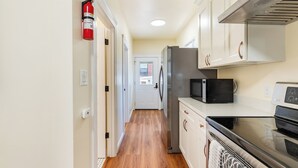 Una cocina con armarios blancos, un refrigerador de acero inoxidable, un microondas y un horno.