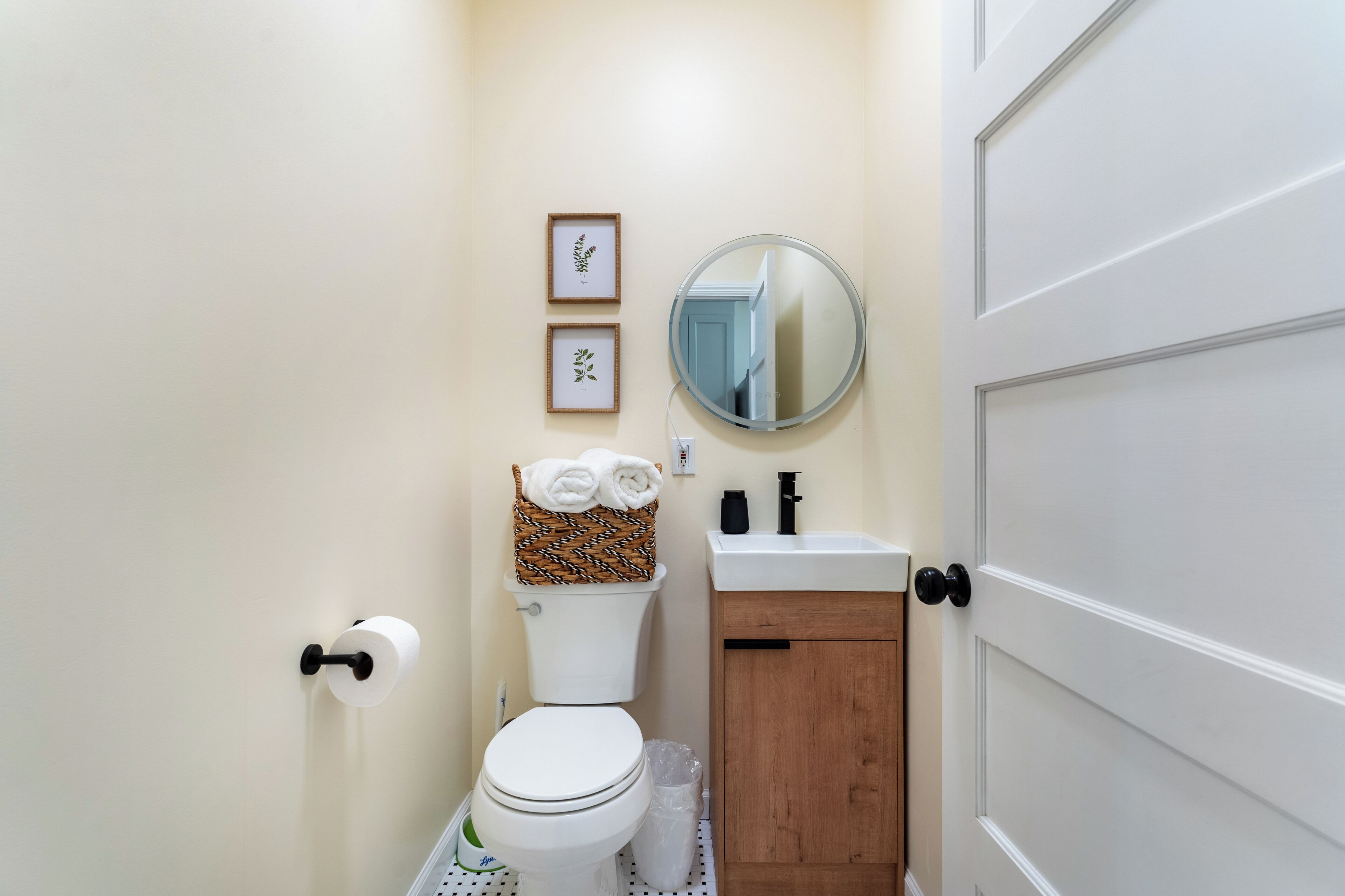 Une salle de bain équipée de toilettes, d’un lavabo, d’un miroir et de tableaux encadrés accrochés au mur.