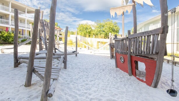 A sandy beach area with wooden play structures and a swing set. - Instant Evasion - Piscine Partagée (La Teste-de-Buch)