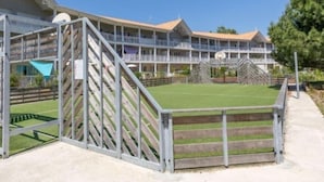 A hotel with a multi-story structure, a basketball court, and a fenced area. - Instant Evasion - Piscine Partagée (La Teste-de-Buch)