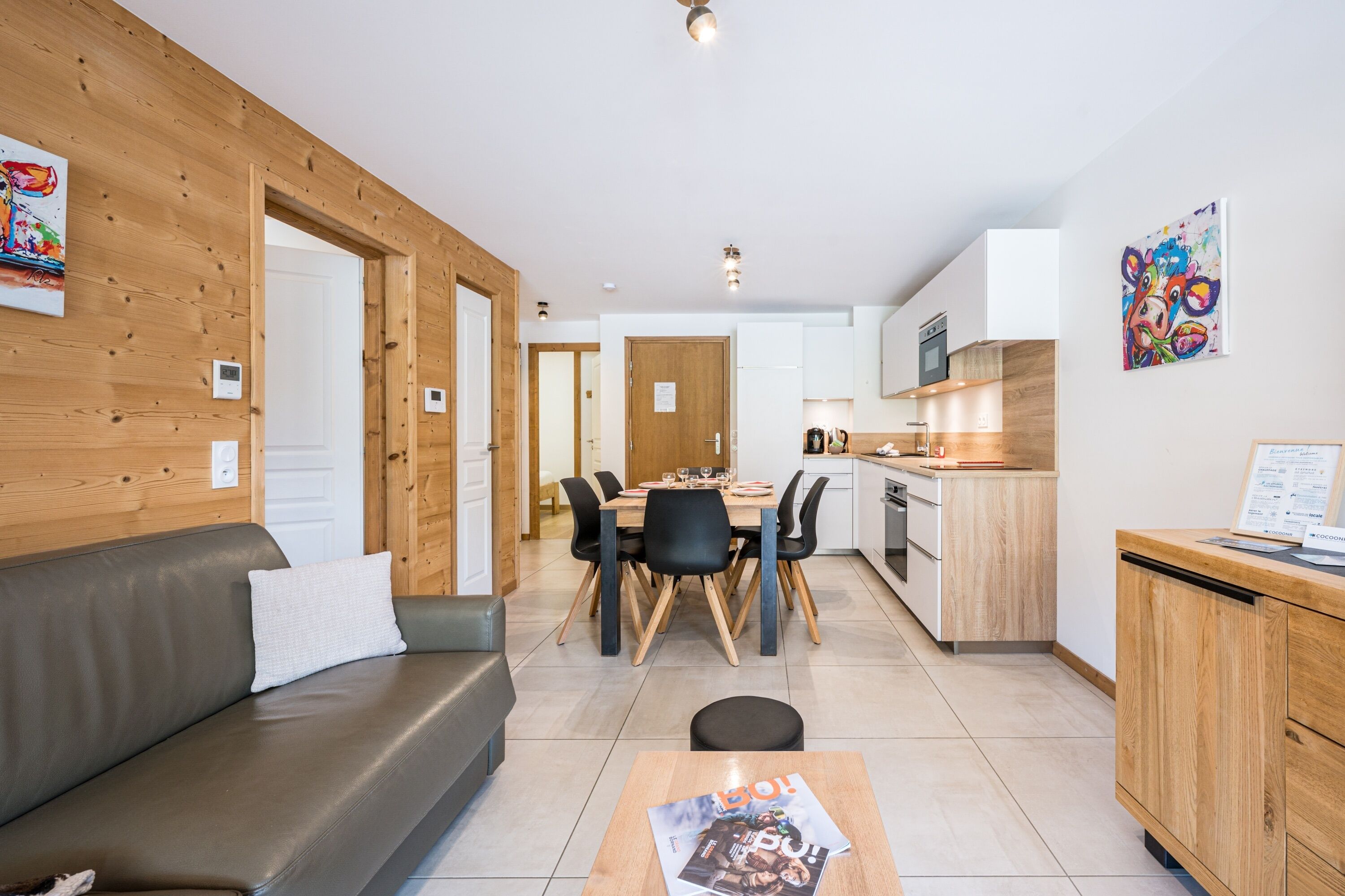 A modern living room with a sofa, dining table, and kitchen area.