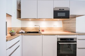Eine moderne Küche mit weißen Schränken, einer Holzarbeitsplatte, einem eingebauten Backofen und einem Geschirrspüler.