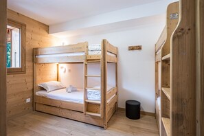 A bunk bed room with a window, a small black trash bin, and wooden walls. - Balcon du soleil n°33 - Balcon avec vue montagne (Le Grand Bornand)