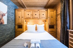 Ein Zimmer in einer Holzhütte mit einem Bett, Kissen und einem Handtuch.
