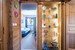 A wooden interior with a bed, a chair, and a shelf with various items. - Mont Blanc - Apt N°1 (Le Grand Bornand)
