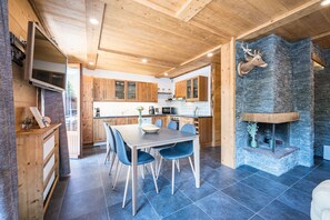 Eine moderne Küche mit Holzschränken, einem Steinofen und einem Essbereich mit blauen Stühlen.