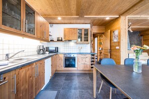 Eine moderne Küche mit Holzschränken, einem eingebauten Backofen und einem Essbereich mit Tisch und Stühlen.