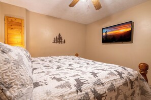A bedroom with a bed, a ceiling fan, a wall-mounted TV, and a small tree decoration. - Full Arcade Game Room, Hot Tub & Mountain Views, Sleeps 10 Near Dollywood (Sevierville)