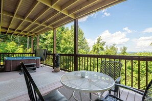 Een overdekt terras buiten met een jacuzzi, zitplaatsen en een tafel.