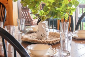 A dining table with clear glassware, a white ceramic owl centerpiece, and a potted plant. - Full Arcade Game Room, Hot Tub & Mountain Views, Sleeps 10 Near Dollywood (Sevierville)
