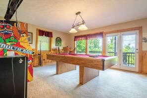 A pool table in a room with a view of greenery outside. - Full Arcade Game Room, Hot Tub & Mountain Views, Sleeps 10 Near Dollywood (Sevierville)