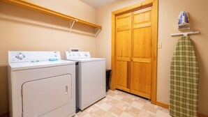 A laundry room with two washing machines, a wooden door, and a drying rack with a green plaid item. - Full Arcade Game Room, Hot Tub & Mountain Views, Sleeps 10 Near Dollywood (Sevierville)