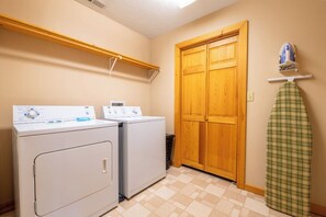 A laundry room with two washing machines, a wooden door, and a drying rack with a green plaid item. - Full Arcade Game Room, Hot Tub & Mountain Views, Sleeps 10 Near Dollywood (Sevierville)