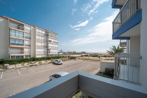 A multi-story building with balconies, a parking lot, and a clear view of the beach. - Le Cocon du Barcarès - Proche Plage (Le Barcarès)