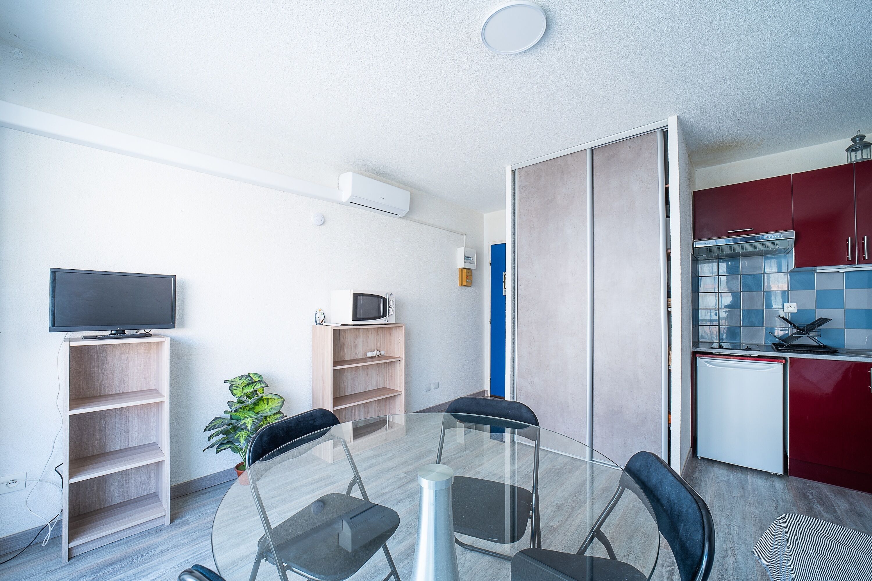 Eine moderne Küche mit roten Schränken, einem weißen Kühlschrank und einer Mikrowelle auf der Arbeitsfläche.