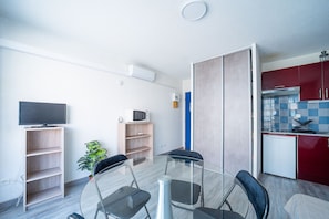 A modern kitchen with red cabinets, a white refrigerator, and a microwave on the countertop. - Le Cocon du Barcarès - Proche Plage (Le Barcarès)