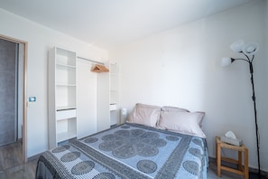 Un dormitorio con cama, armario, mesita de noche y lámpara de pie.