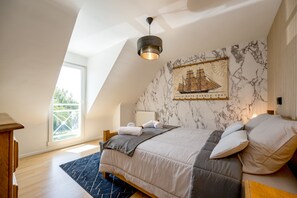 Ein Schlafzimmer mit einem großen Bett, einer Deckenleuchte, einem Fenster und einem Wandbild.