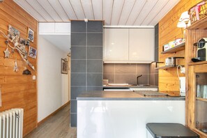 A modern kitchen with wooden walls, a central island, and a built-in oven.