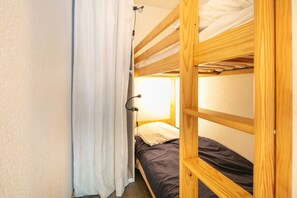 A bunk bed room with a curtain, a bedside lamp, and a wooden headboard.